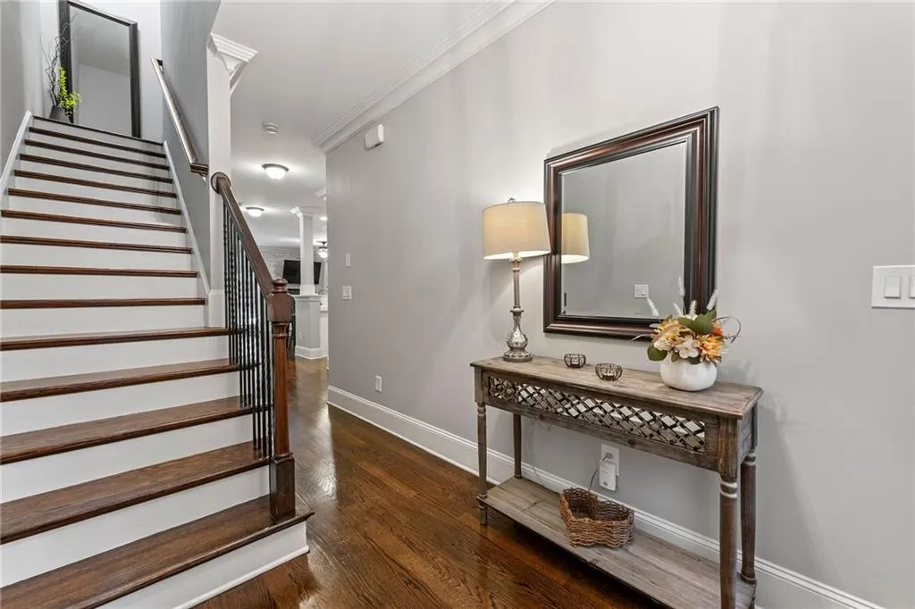 Stairs featuring ornamental molding, decorative columns, and hardwood / wood-style floors