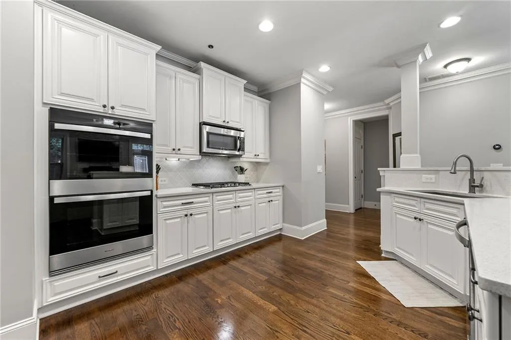 Kitchen featuring ornamental molding, sink, white cabinetry, appliances with stainless steel finishes, and dark hardwood / wood-style floors
