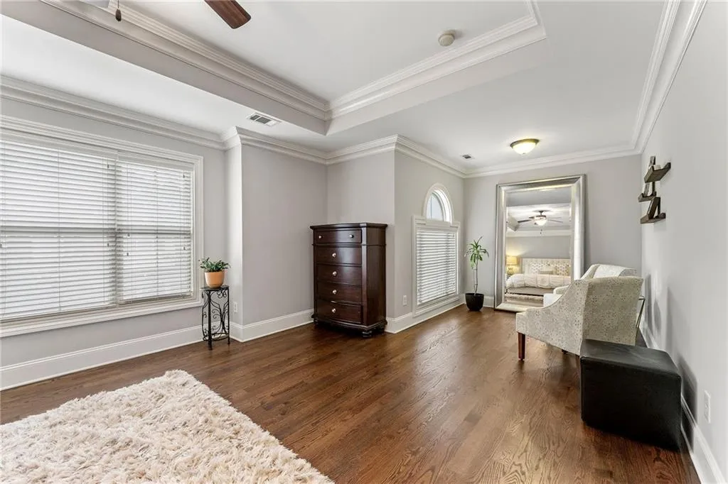 Living area featuring dark hardwood / wood-style flooring, ceiling fan, a raised ceiling, and crown molding