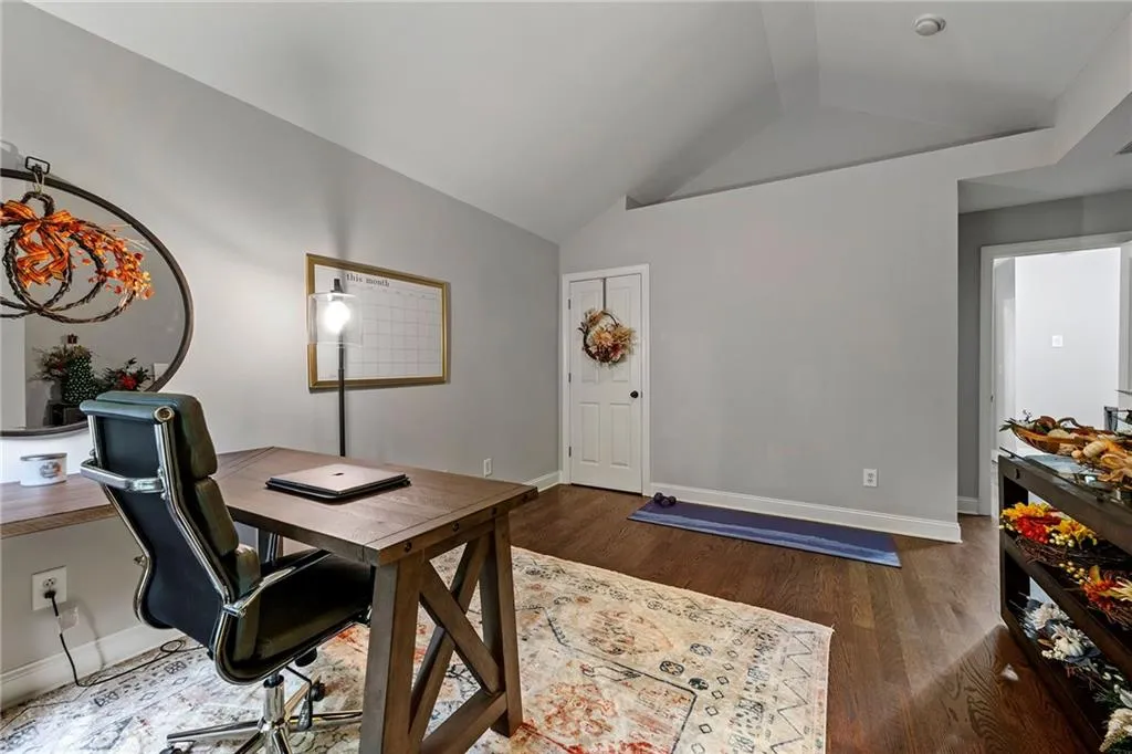 Home office with vaulted ceiling and dark wood-type flooring