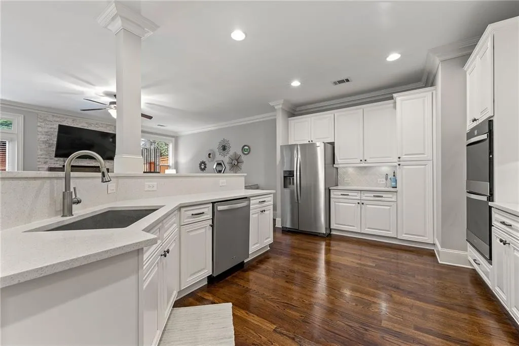 Kitchen featuring white cabinets, dark hardwood / wood-style flooring, stainless steel appliances, crown molding, and sink