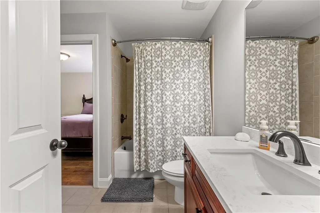 Full bathroom featuring shower / tub combo, tile patterned floors, vanity, and toilet