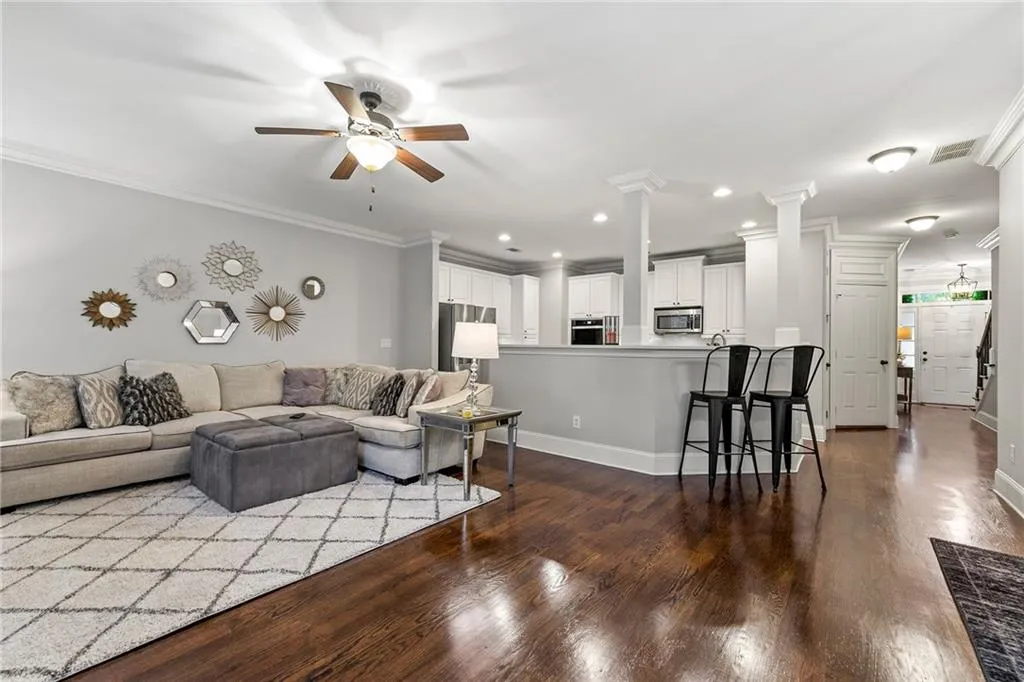 Living room featuring ceiling fan, ornate columns, crown molding, and hardwood / wood-style floors