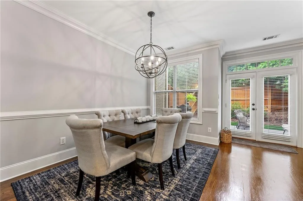 Dining room featuring french doors, ornamental molding, a notable chandelier, and dark wood-type flooring