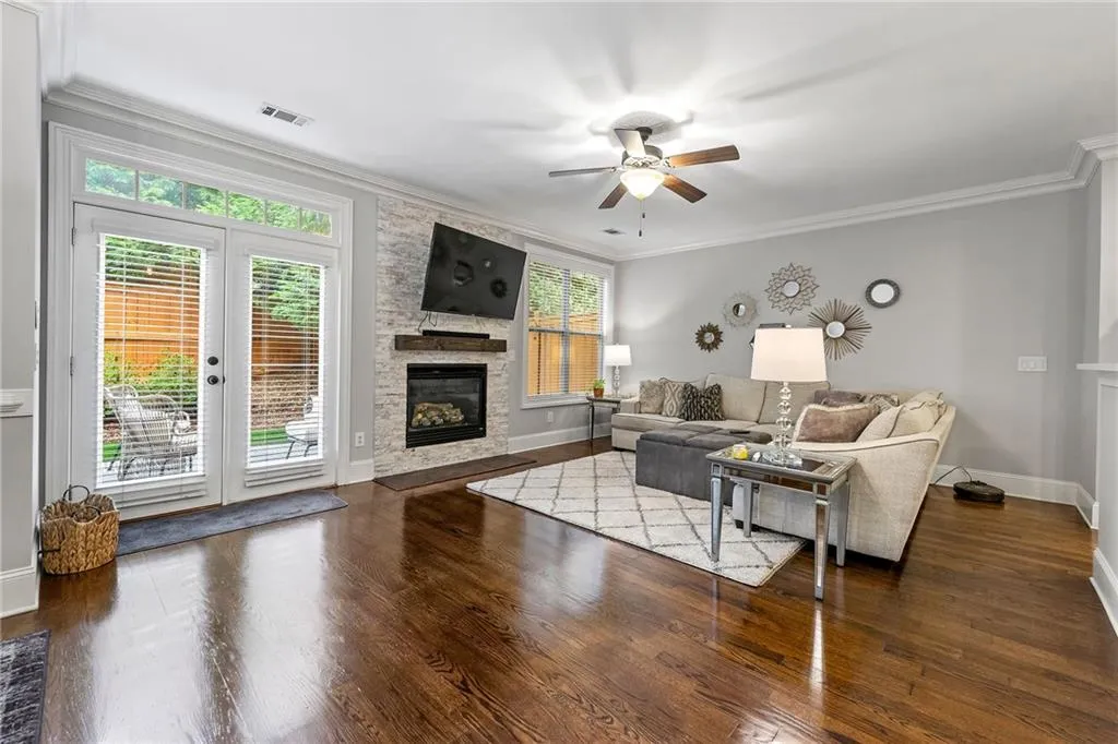 Living room with a stone fireplace, ornamental molding, and dark hardwood / wood-style flooring