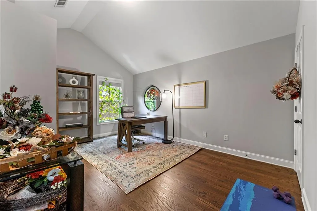 Office space featuring vaulted ceiling and dark hardwood / wood-style flooring