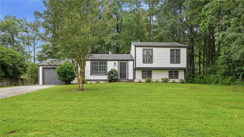 White siding exterior with dark trim accents and an attached garage