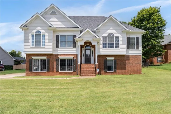 Two-story residence featuring a brick foundation and white siding