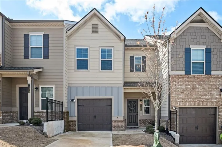 Townhome / multi-family property featuring an attached garage, brick siding, driveway, and board and batten siding
