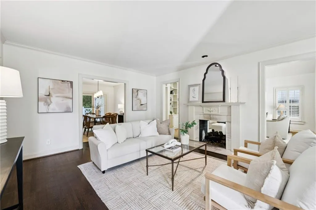 Living room featuring a fireplace with flush hearth, dark wood-style floors, plenty of natural light, and ornamental molding