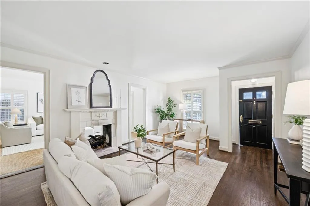 Living room featuring dark wood-type flooring, crown molding, and a fireplace