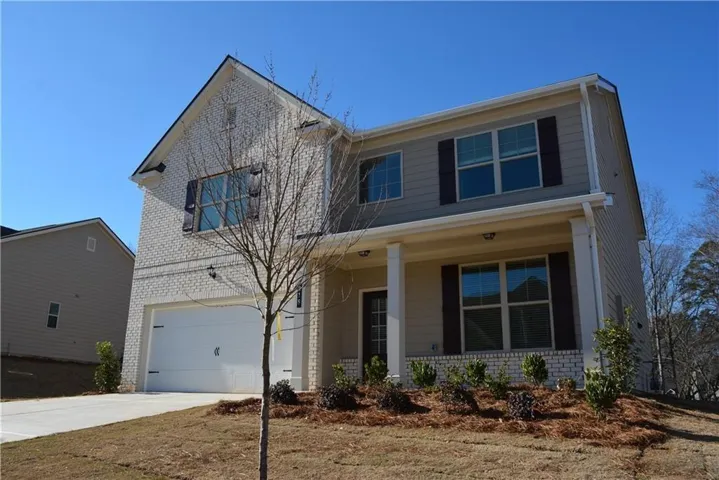 View of front of property featuring brick siding, covered porch, an attached garage, and concrete driveway
