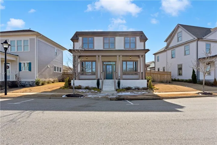 Classic Colonial-style residence featuring a welcoming front porch with decorative railings, multi-pane double-hung windows, and a symmetrical facade finished in neutral exterior siding