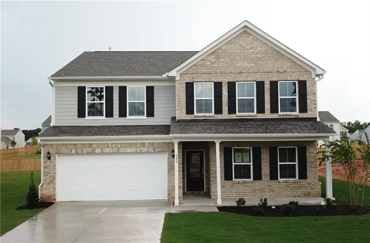 Two-story residence featuring a brick facade, gray siding, a covered entry porch, an attached two-car garage, and a concrete driveway