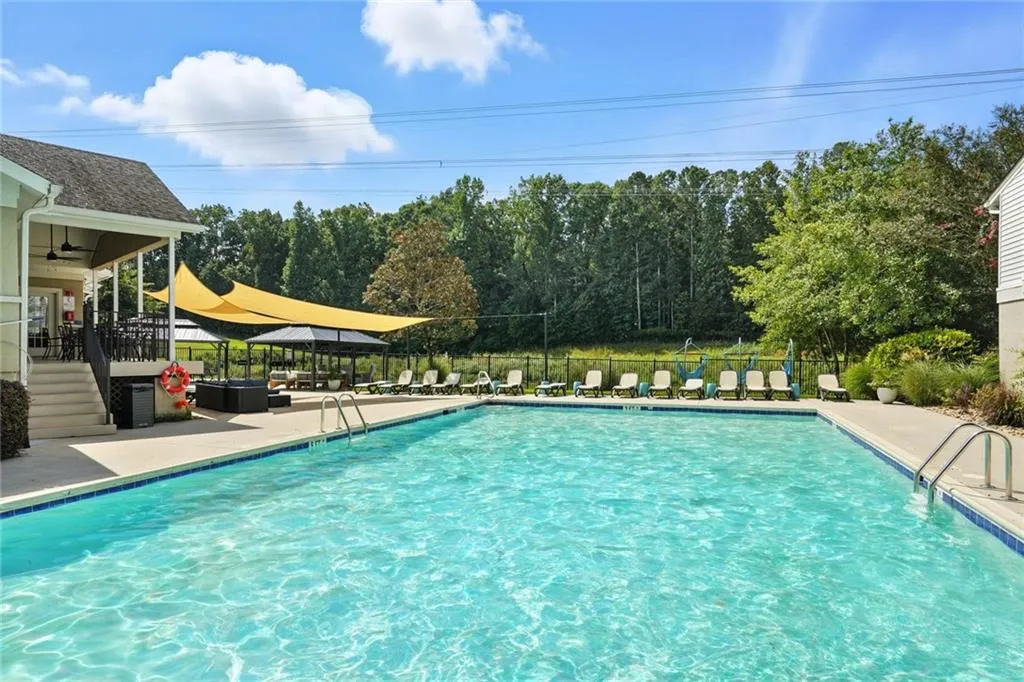 Community pool with a patio area, view of scattered trees, a ceiling fan, and stairs