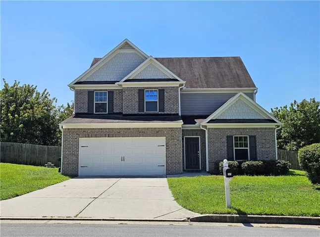 Brick and siding exterior with gabled accents, attached two-car garage, concrete driveway, and established front landscaping