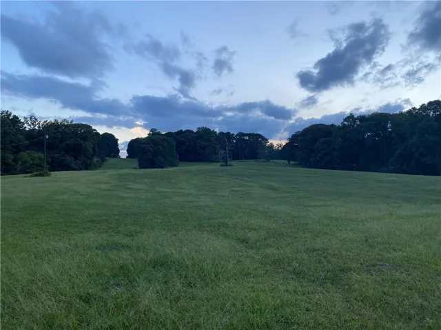 View of community with a lawn, a rural view, and a view of trees