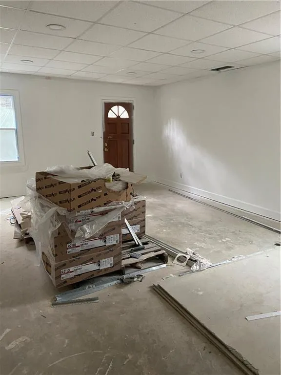 Unfurnished living room featuring concrete floors and a drop ceiling