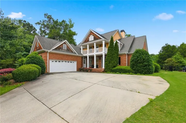 Brick exterior with a prominent two-story porch, a two-car garage, and a concrete driveway