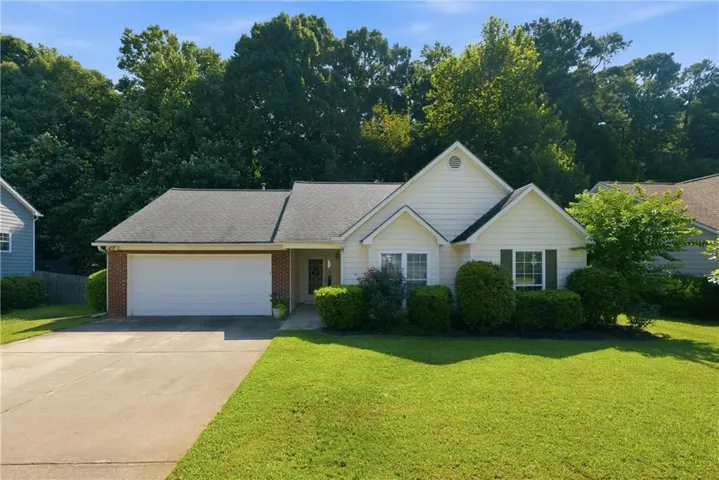 Single-story residence featuring a two-car garage, brick accents, and a well-maintained lawn