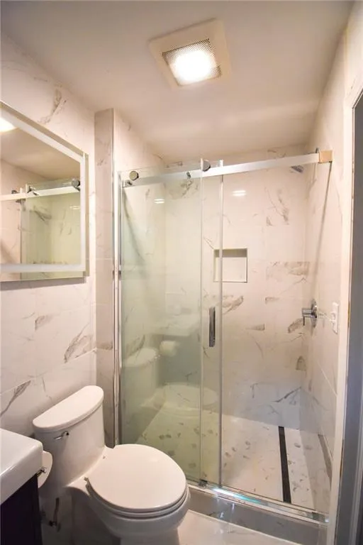 Newly refinished bathroom with glass shower door and casement window.
