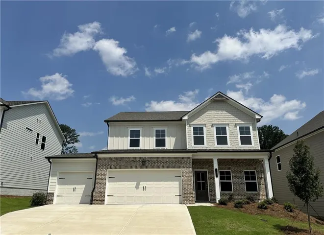 Two-story residence featuring a brick and siding exterior, a two-car garage, and an additional single-car garage