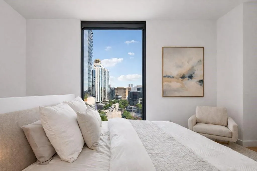 Bedroom with floor to ceiling windows and a city view