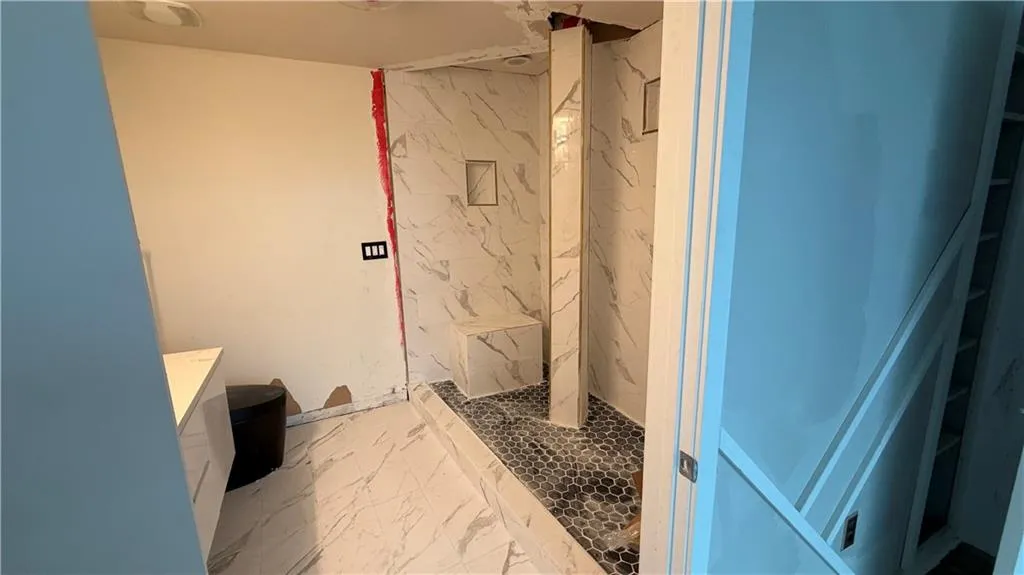 Bathroom with a marble finish shower, vanity, and light marble finish floors