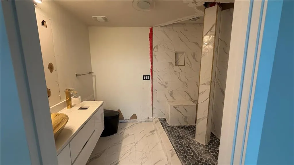 Full bathroom with light marble finish flooring, vanity, and a marble finish shower