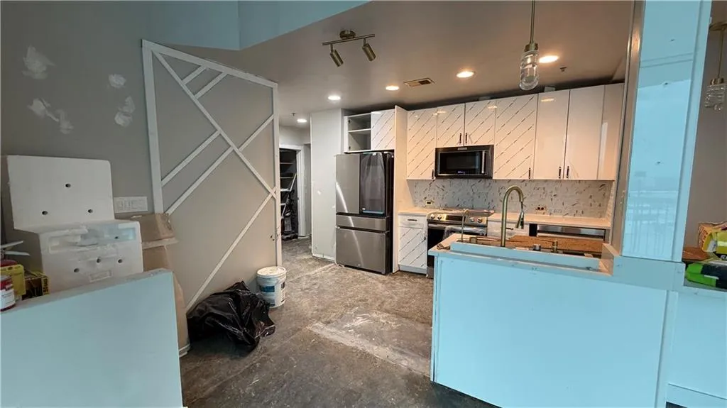 Kitchen with white cabinets, stainless steel appliances, open shelves, tasteful backsplash, and recessed lighting