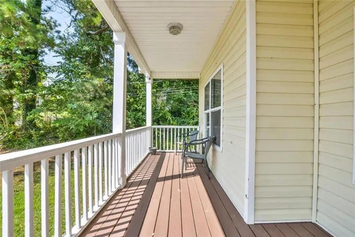 Covered porch featuring wood-finish flooring, white railing, and exterior siding