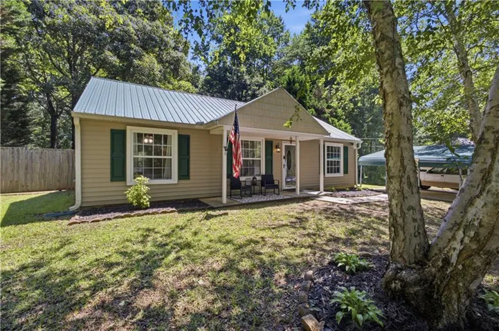 Exterior residence featuring a light-colored siding, a metal roof, and green window shutters