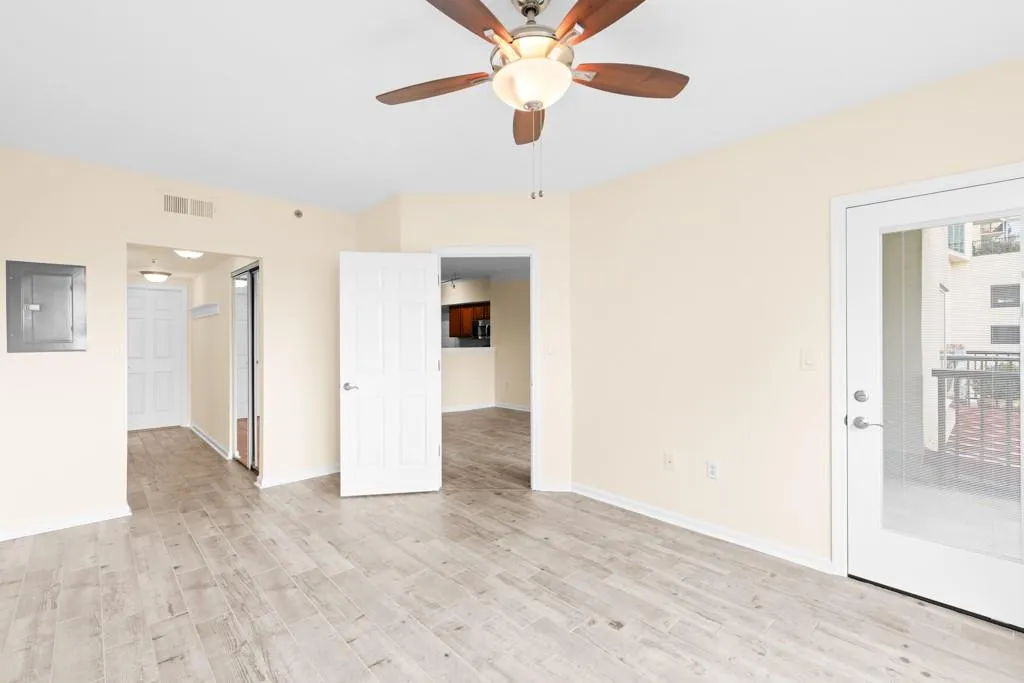 Spare room with ceiling fan, electric panel, visible vents, baseboards, and light wood-style floors