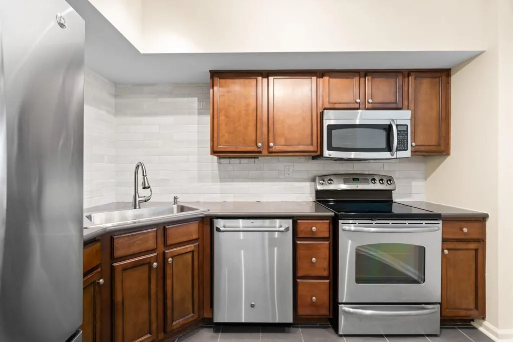 Kitchen featuring a sink, decorative backsplash, brown cabinetry, and stainless steel appliances