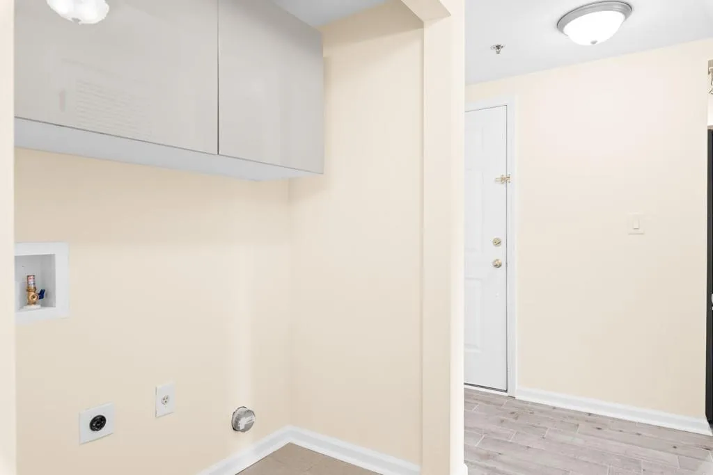 Laundry area with washer hookup, electric dryer hookup, cabinet space, baseboards, and light wood-style flooring