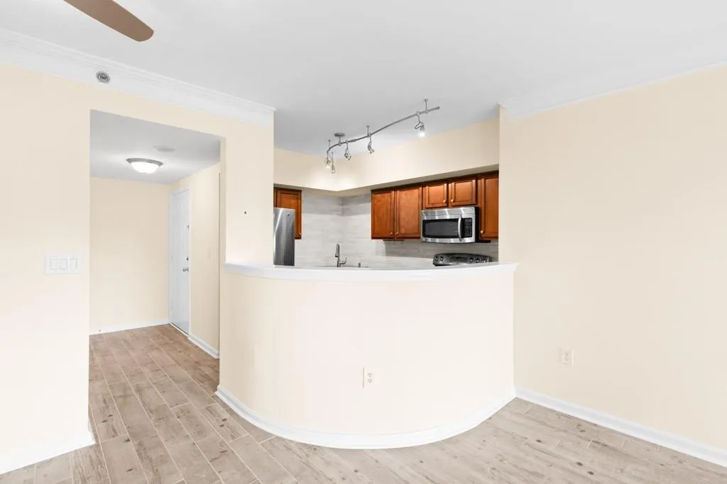 Kitchen featuring brown cabinets, appliances with stainless steel finishes, tasteful backsplash, and light wood-type flooring