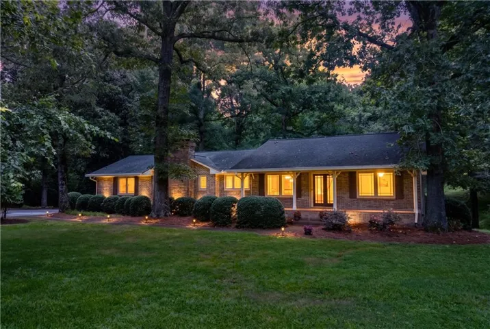 Brick ranch-style residence featuring a dark shingle roof and a prominent front entrance with sidelights