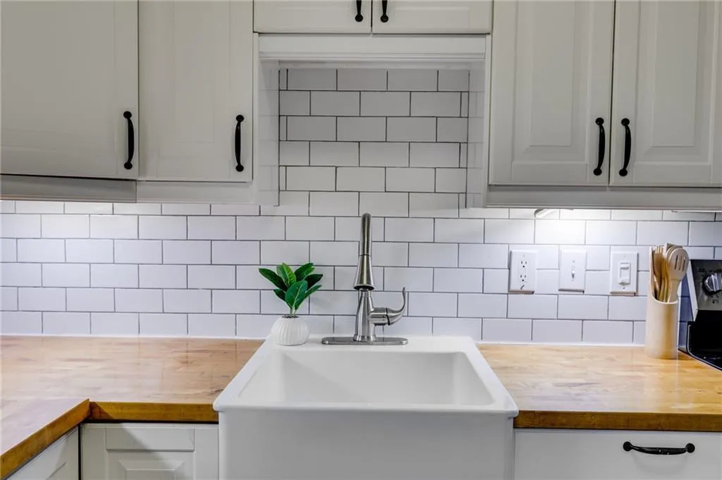 Kitchen featuring backsplash, white cabinetry, butcher block counters, and black stove