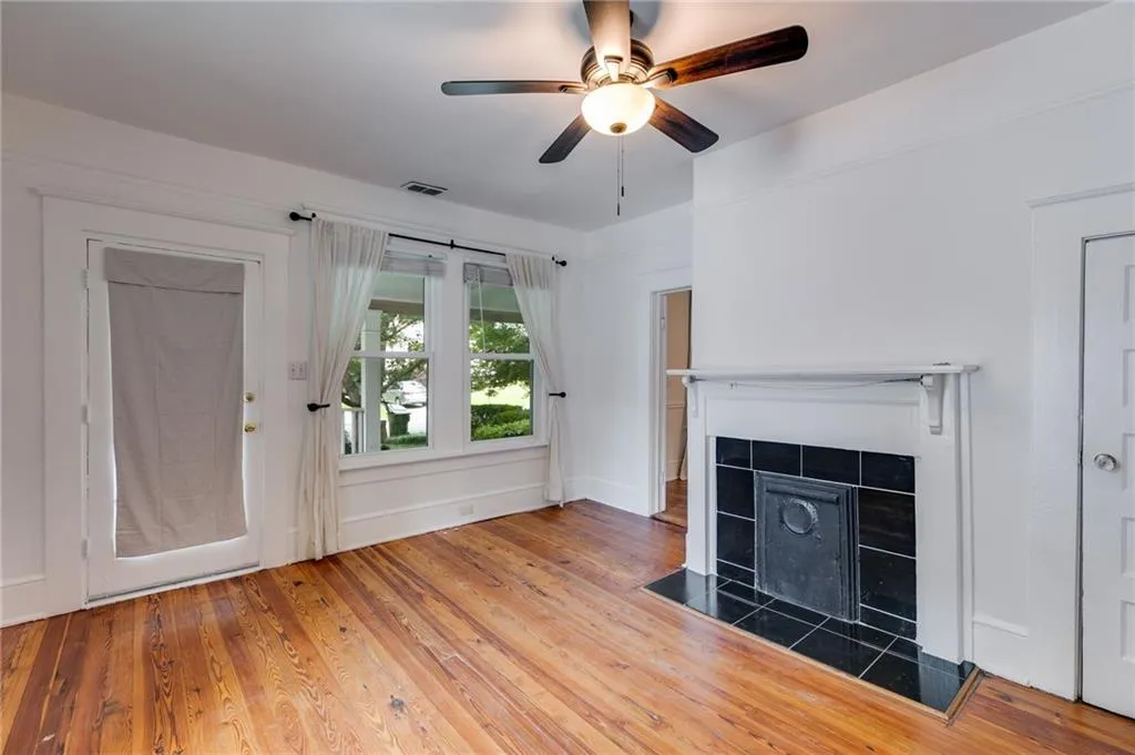 Unfurnished living room with hardwood / wood-style floors, a tiled fireplace, and a ceiling fan