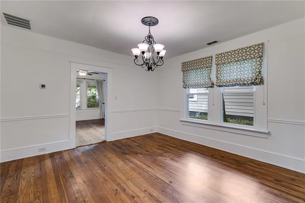 Unfurnished dining area with a chandelier, dark wood-type flooring, and a ceiling fan