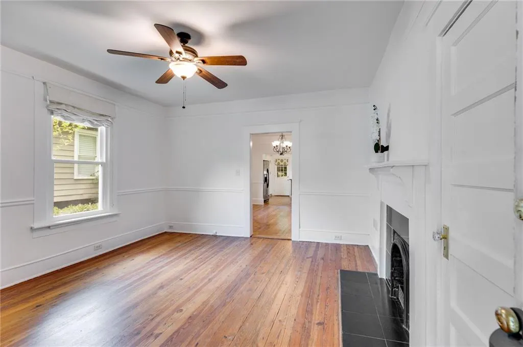 Unfurnished living room featuring hardwood / wood-style flooring, a chandelier, a fireplace with flush hearth, and a ceiling fan
