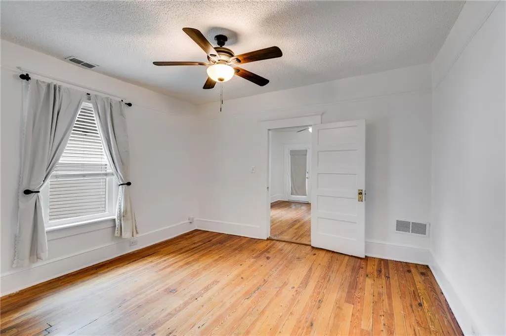 Spare room featuring light wood-type flooring, a textured ceiling, and a ceiling fan