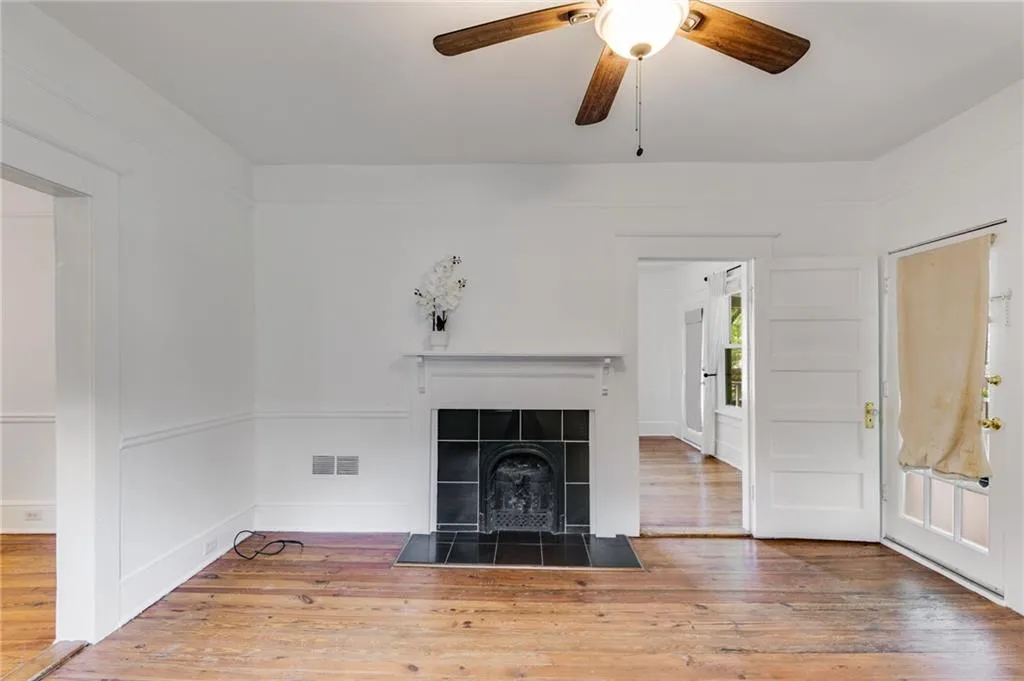 Unfurnished living room with light wood-style flooring, a tiled fireplace, and ceiling fan