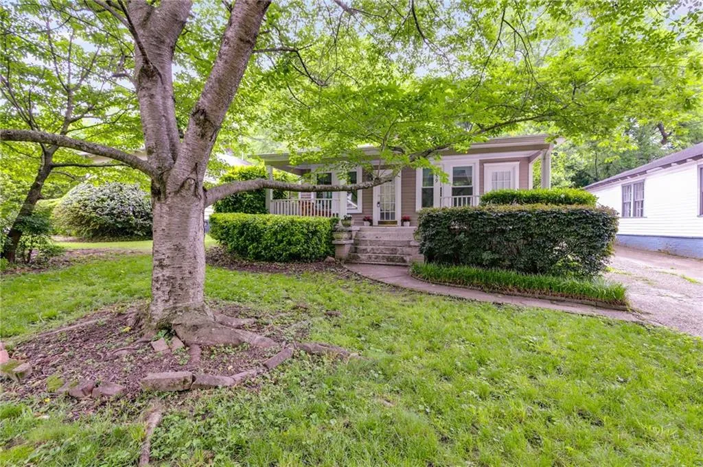 View of property hidden behind natural elements featuring a front yard