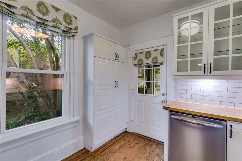Kitchen featuring wooden counters, glass insert cabinets, stainless steel dishwasher, and light wood finished floors