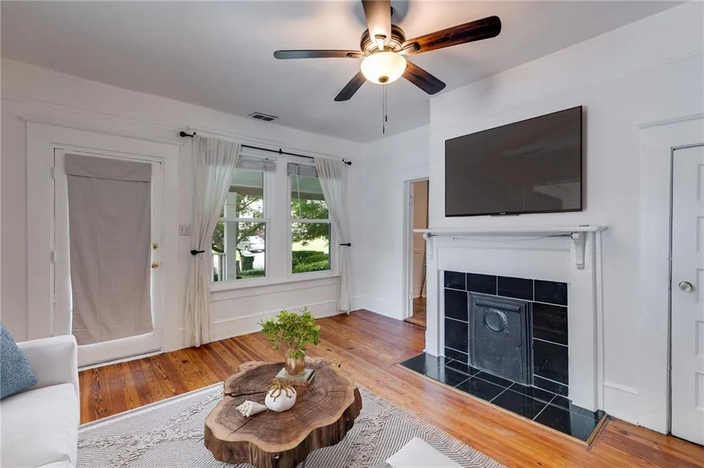 Living room with wood finished floors, a tile fireplace, and a ceiling fan