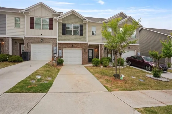 Townhome exterior featuring brick and siding accents, private driveways, and integrated single-car garages
