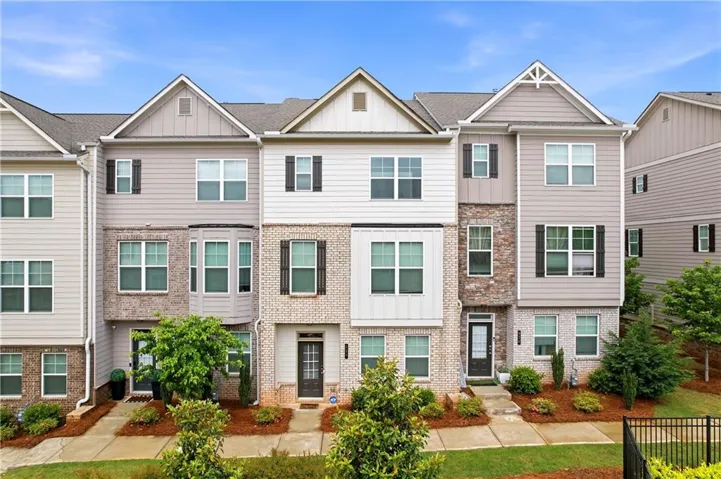 Three level townhome featuring a mixed-material facade with brick and siding, multiple gables, and bay window