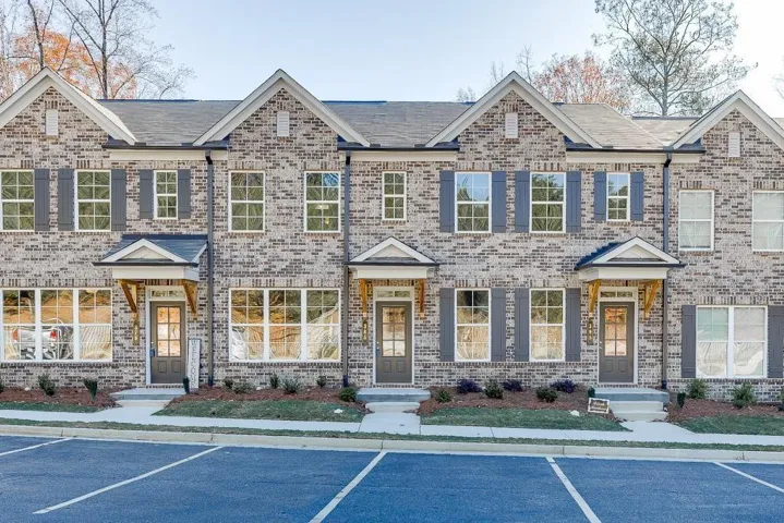 Brick exterior featuring dark shutters, covered entryways, and multiple windows
