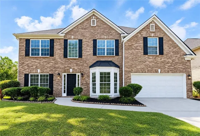 Brick veneer exterior with a two-car garage, bay window, landscaped front yard, and a concrete driveway